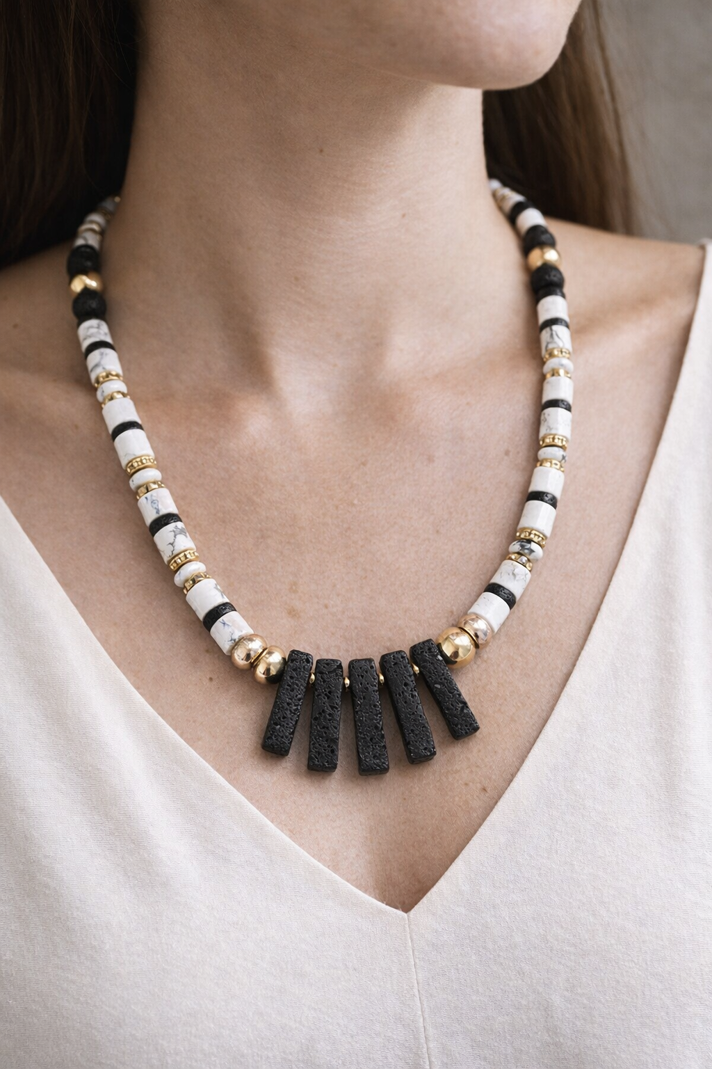 Lava stone and gold necklace styled on olive wood